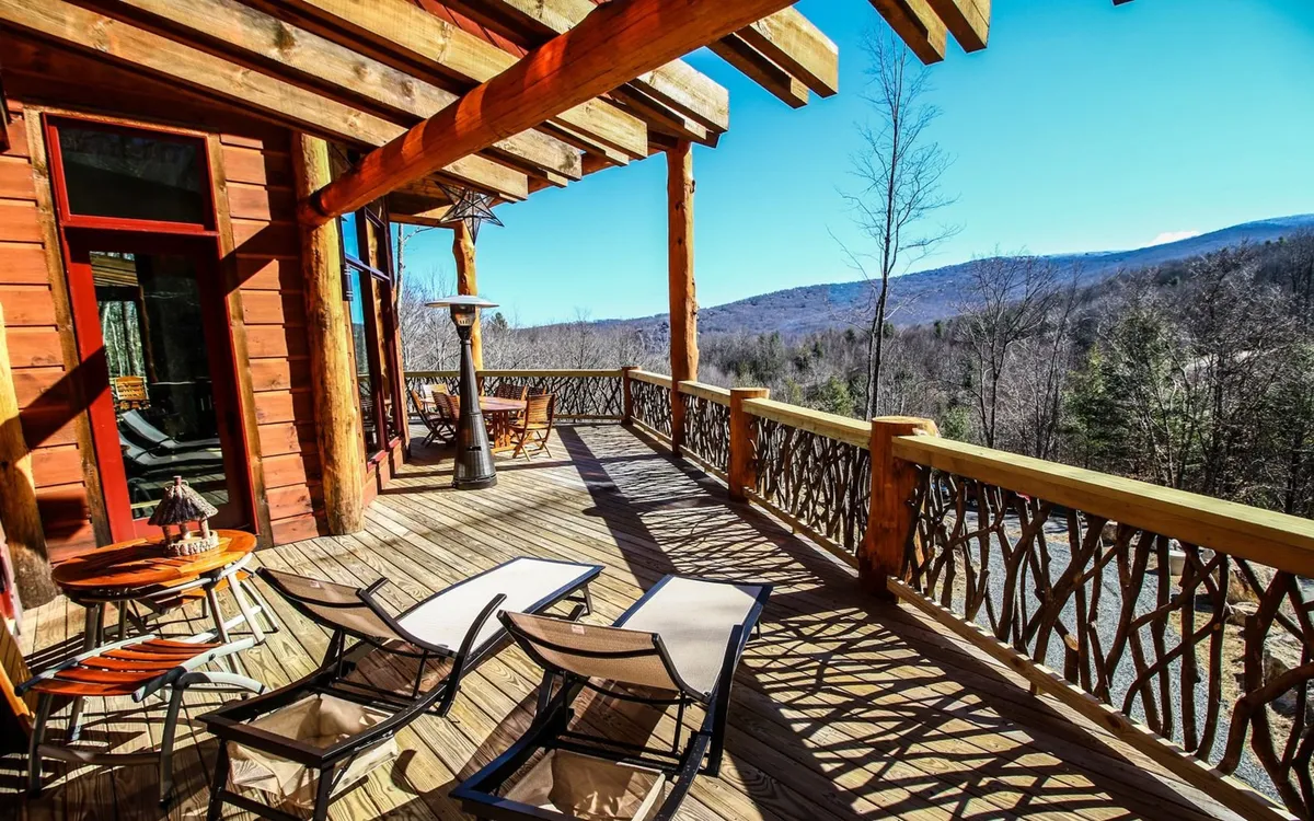 This serene exterior shot captures a spacious wooden deck equipped with comfortable lounge chairs and a decorative railing, set against a breathtaking mountain backdrop. The setting is perfect for relaxing, socializing, or simply soaking in the panoramic vistas mentioned in the section.